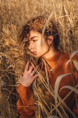 Portrait of beautiful young woman outdoor posing while holding a bouquet of reeds and feels emotional