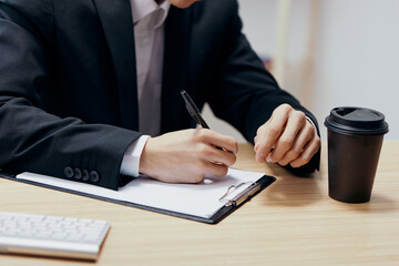 business man sitting at the table fills out documents close-up