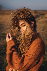 A mysterious portrait of a beautiful young woman with curly hair while enjoying the sun