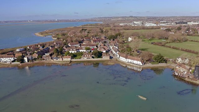 Aerial footage over Langstone Harbour towards a row of traditional English cottages in an area to the south of Havant on the waterfront of the harbour.