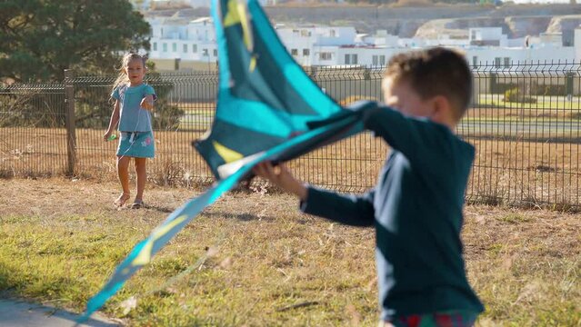 Ni&ntilde;os felices jugando volando el papalote el cometa con el aire disfrutando en el parque al aire libre en el exterior aprendiendo conociendo el mundo