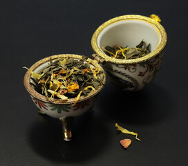 Herbata liściasta z płatkami kwiatów - w jajku - na Wielkanoc, wielkanocna herbatka. Naczynie w kształcie jajka, malowane i złocone. - obrazy, fototapety, plakaty