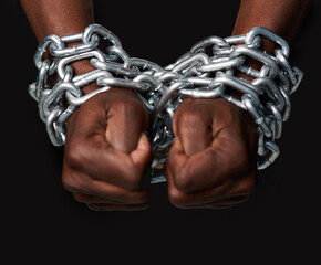 Slave to the system. Cropped shot of a mans hands tied up with chains against a black background.