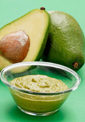 Fresh avocado cream bowl on avocado fruits background.