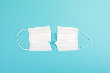 Covid-19 mask cut into two pieces with a scissor, end of pandemic, back to normal, epidemic
