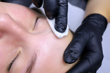 close-up of the master's hand in black gloves removes the compositions for laminating eyebrows with...
