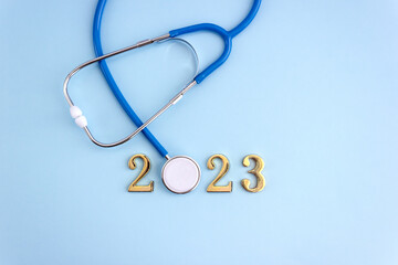 Medicine stethoscope and numbers 2023 on blue background. Happy New Year medical calendar cover.
