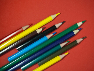 Colored wooden pencils on colored paper. Sharpened pencils. Drawing tool.  Accessories for creativity.