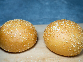 Bun with sesame seeds.  Table in the bakery. White bun on a cutting board. Products made from wheat flour of the highest grade.
