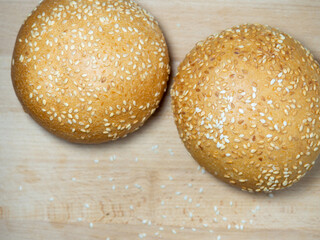 Bun with sesame seeds. Bakery products. Table in the bakery. White bun on a cutting board.