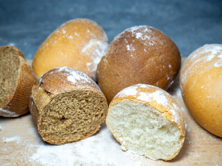 Slaced bakery products. Table in the bakery. Buns on a cutting board. Rye and wheat buns. Products from premium wheat flour and rye flour.