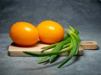 Orange greenhouse tomatoes on the kitchen board.  Tomatoes with chives