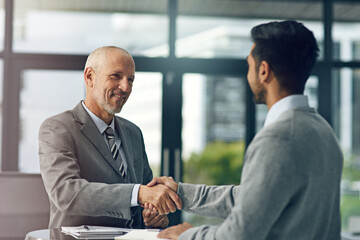 Glad to have you on board. Cropped shot of two businessmen shaking hands in an office.