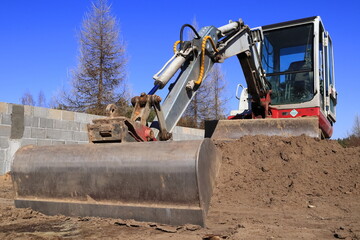 Naklejka premium Koparka przy budowie domu. Excavator at the construction of the house.