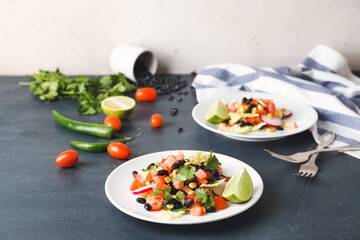 Plates of Mexican vegetable salad and ingredients on table