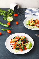 Plates of Mexican vegetable salad and ingredients on table