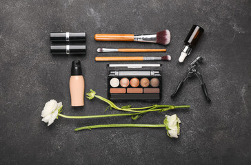 Composition with cosmetics, makeup supplies and ranunculus flowers on dark background