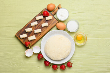Composition with raw lazy dumplings, ingredients and ripe strawberry on color wooden background