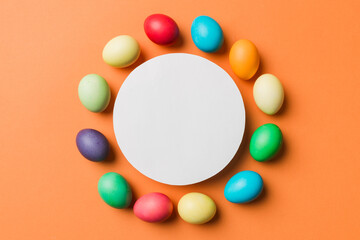 round frame multicolored Easter eggs with white blank paper on a brown background, close-up, space for text, blank for design, selective focus, tinted image