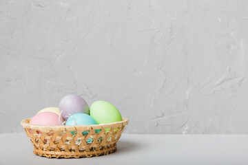 Multi colors Easter eggs in the woven basket on colored background . Pastel color Easter eggs. holiday concept with copy space