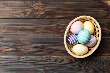 Multi colors Easter eggs in the woven basket on colored background . Pastel color Easter eggs. holiday concept with copy space