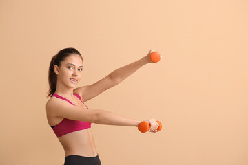 Fototapeta premium Sporty teenage girl with dumbbells on beige background