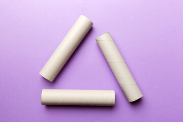 Empty toilet paper roll on colored background. Recyclable paper tube with metal plug end made of kraft paper or cardboard in the form of a recycling sign