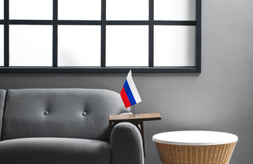 Russian flag on sofa and table near grey wall