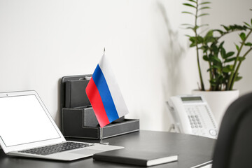 Fototapeta premium Russia flag, notebook, organizer and laptop on dark table near light wall