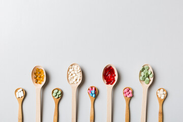 Top view Variety of vitamin and mineral pills in wooden spoon on Colored background. Top view of assorted pharmaceutical medicine pills. Dietary supplement healthcare product
