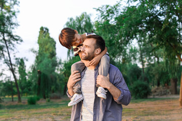 Fototapeta premium Father carrying his little son in park