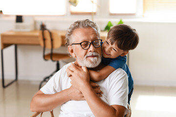 Little boy hugging his grandfather at home - Powered by Adobe