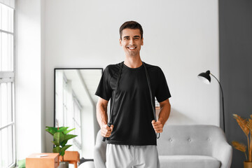 Sporty young man with skipping rope at home