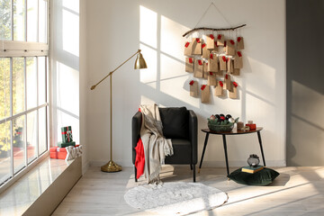 Comfortable armchair, table and advent calendar hanging on white wall in room