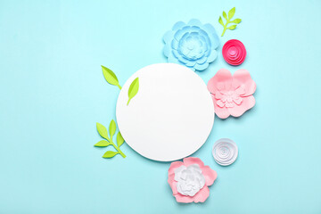 Beautiful handmade paper flowers and blank paper sheet on blue background