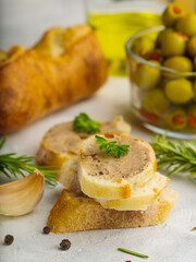 Close-up. French foie gras baguette sandwiches garnished with parsley leaves, green olives, baguette and rosemary sprigs on a white background. Festive dish. French cuisine...