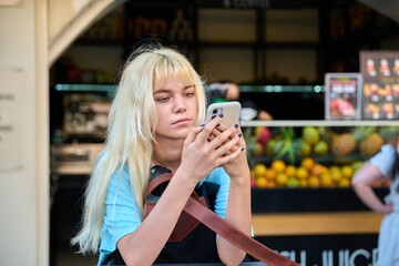Teenage girl 16, 17 years old with a smartphone in the city.
