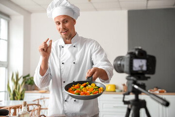 Male chef with fried vegetables recording video in kitchen