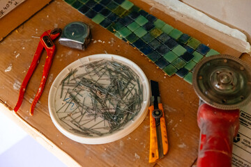 Used old tools, retractable utility knife, pliers, metal nails used for applying mosaic tiles. Renovation concept.