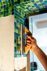 Applying mosaic tiles in bathroom, sauna walls. Construction tools and equipment. Spa or sauna...