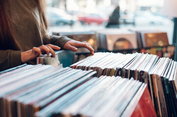 Mains de femme choisissant un disque vinyle dans un magasin de disques