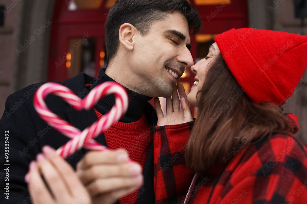 Poster Loving couple with candy canes touching noses on winter day, closeup