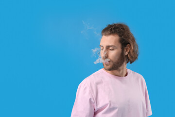 Smoking young man on blue background