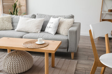 Modern table with sofa and pouf in interior of room