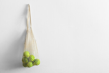 String shopping bag with ripe bergamot fruits hanging on light wall