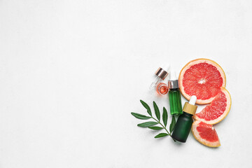 Bottles of grapefruit oil on light background