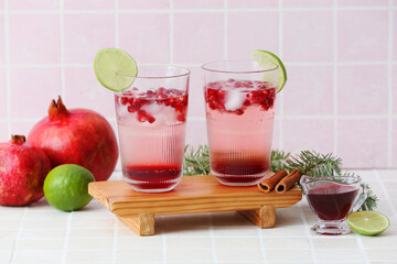 Glasses of tasty pomegranate cocktail on tile background