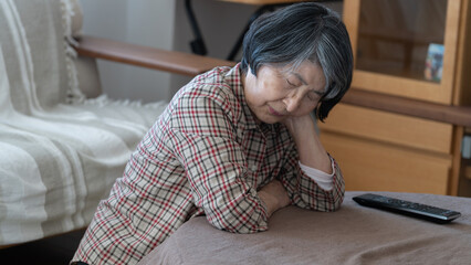 疲れてこたつで頬杖をついて寝ている80代のシニア女性