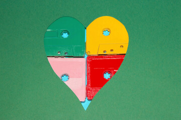 heart in green background filled with music cassettes in four colors, yellow green pink and red, creative art music love wallpaper with copy space
