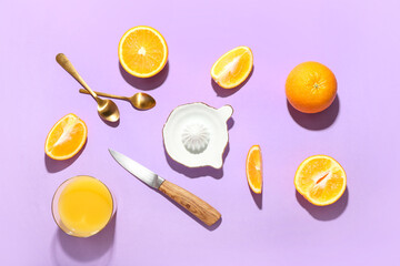 Fototapeta na wymiar Ceramic juicer, knife, spoons and oranges on purple background
